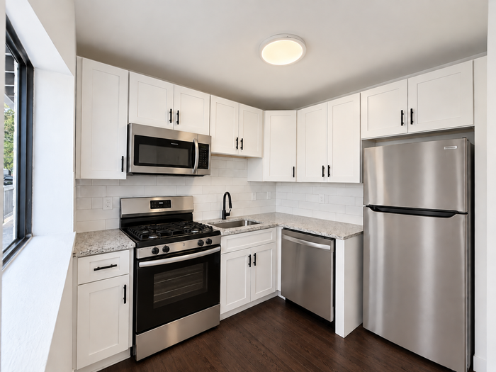 Modern kitchen with sleek stainless steel appliances, marble countertops, and stylish white cabinetry offering a bright and welcoming cooking space.