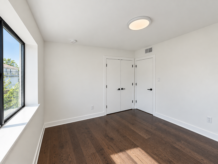 Bright, modern room with sleek hardwood floors, clean white walls, and large window flooding natural light.