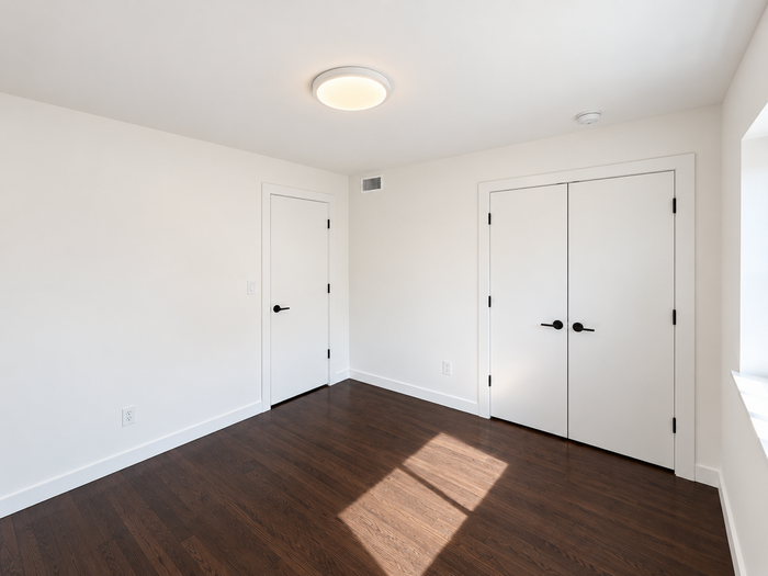 Bright and spacious empty room with elegant hardwood floors and crisp white walls, perfect for a cozy bedroom or office.