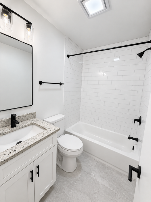 Modern bathroom featuring elegant white subway tile, sleek granite countertop, and stylish black fixtures.
