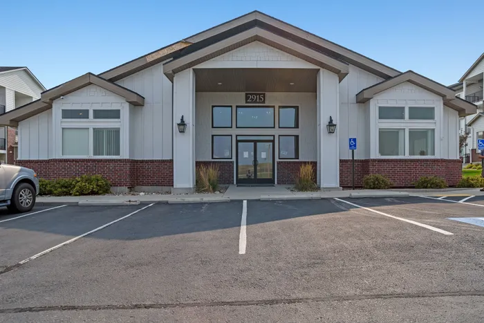 Charming apartment complex entrance with contemporary architecture, featuring large windows and a welcoming path.