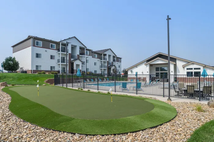Modern apartment complex with a vibrant pool area and a putting green, offering a luxurious and relaxing lifestyle for residents.