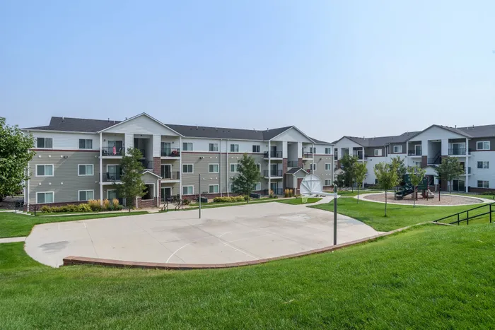 Charming modern apartments with spacious balconies, surrounded by lush greenery and featuring a basketball court and playground, offering a vibrant community living experience.