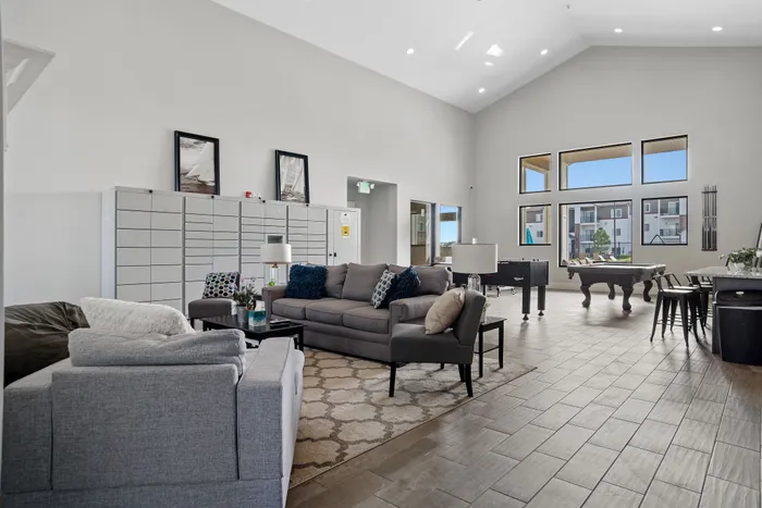 Inviting open-concept lounge area with plush grey sofas and modern decor, featuring large windows offering bright, natural light.