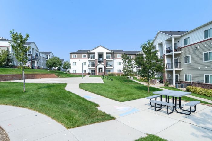 Charming apartment exterior with lush green lawns, offering a tranquil setting and modern architecture.