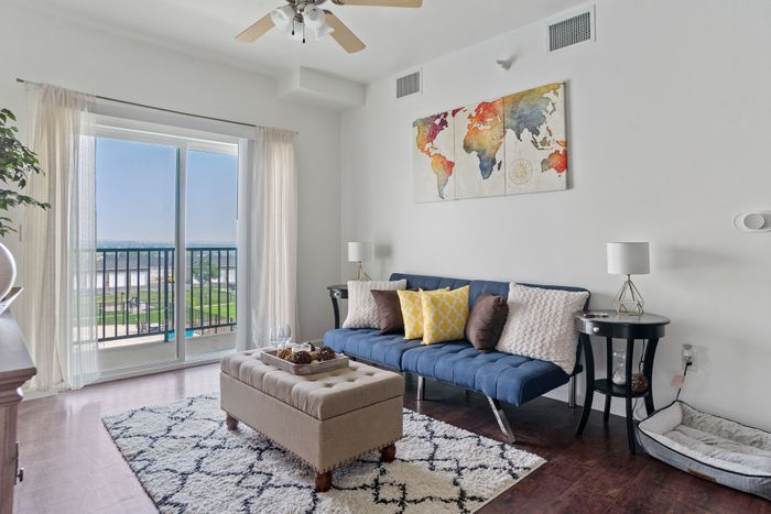 Inviting living room with cozy seating, vibrant wall art, and a stunning balcony view of the water and lush greenery.