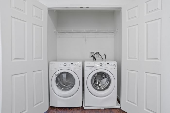 Modern laundry area with sleek front-loading washer and dryer, featuring convenient shelving in a cozy closet space.