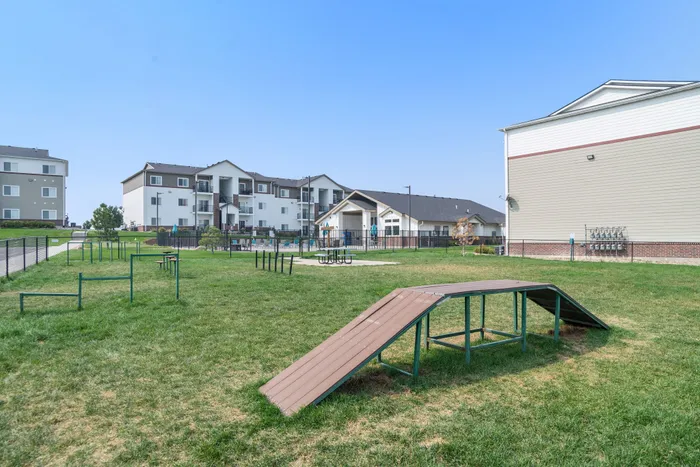 Charming residential complex with modern apartments, featuring a lush green dog park and recreational area.