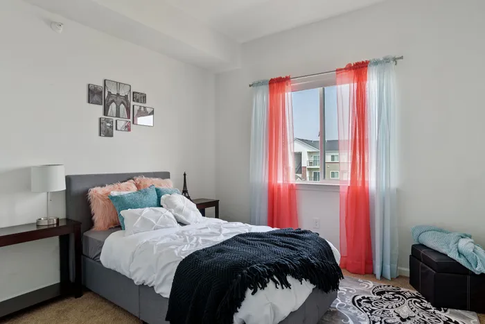 Charming bedroom with stylish decor, plush pillows, and colorful curtains, offering a cozy and inviting atmosphere.