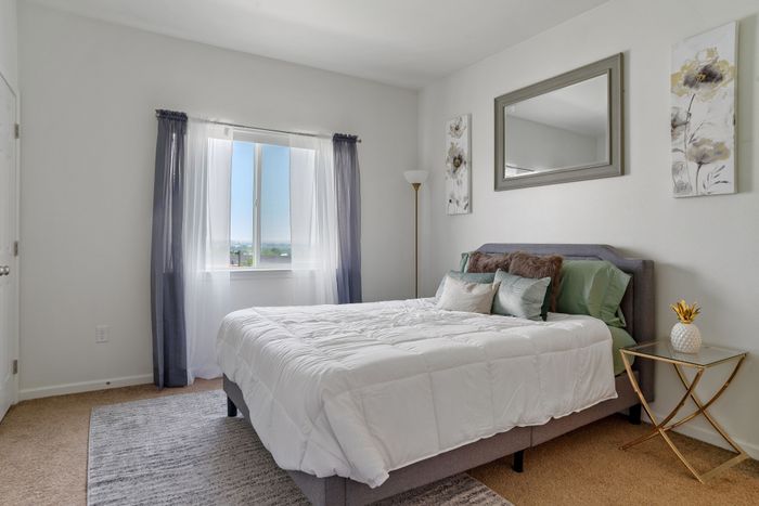 Bright and cozy bedroom featuring a comfortable bed, elegant decor, and a scenic window view.