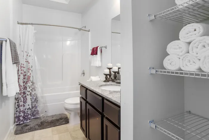 Luxurious bathroom featuring a granite countertop, elegant candles, and a chic shower curtain, perfect for relaxation.