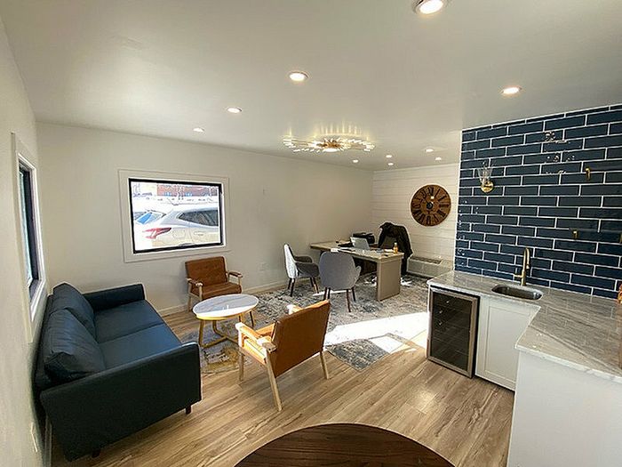 Modern open-plan living space featuring a chic kitchen with deep blue tiled backsplash, stylish seating area, and elegant lighting.