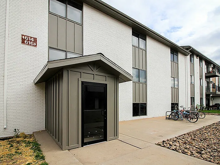 Modern apartment building exterior with sleek entrance, large windows, and convenient bike storage.
