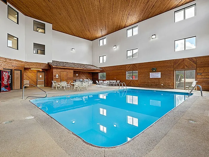Inviting indoor pool area with wooden accents, ample natural light, and comfortable seating, perfect for relaxation and gatherings.