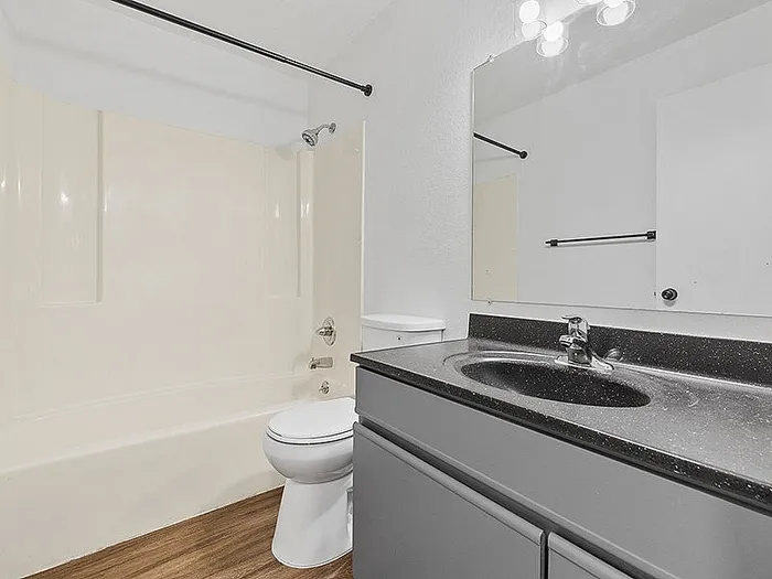 Modern bathroom with sleek fixtures, large mirror, and elegant granite countertop for a luxurious feel.