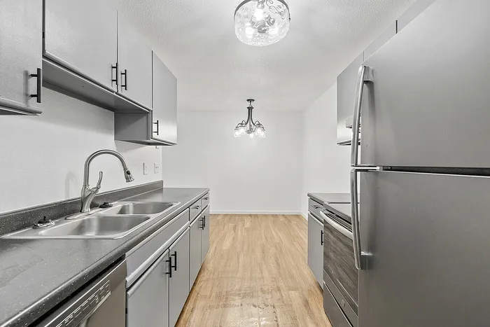 Modern kitchen with sleek gray cabinets, luxurious granite countertops, stainless steel appliances, and elegant lighting in a spacious layout.