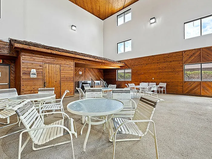 Spacious indoor community area with stylish wood accents, featuring multiple tables and chairs, perfect for social gatherings and relaxation.