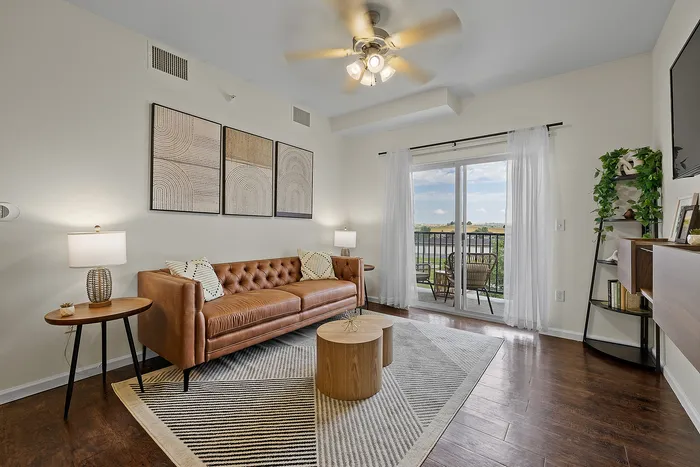 Chic living room with a stylish leather sofa, artistic wall decor, and a cozy balcony view.