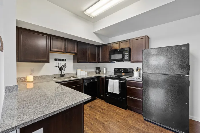 Modern kitchen with elegant dark wood cabinets, sleek granite countertops, and stainless appliances, perfect for culinary creativity.