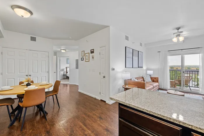 Modern open-plan living dining area with elegant furniture, hardwood floors, and a balcony view offering natural light.