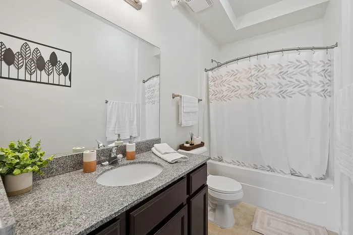 Inviting bathroom with elegant granite countertop, chic modern decor, and a stylish leaf-patterned shower curtain.