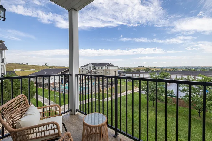 Charming balcony view overlooking lush landscape and modern apartments, perfect for relaxing and unwinding.