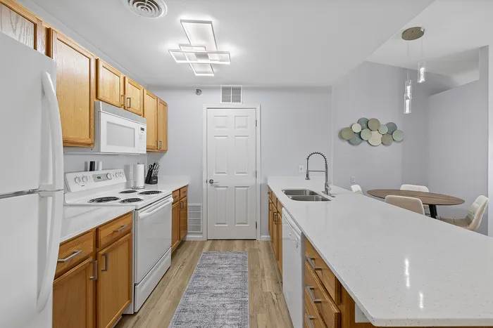 Modern kitchen with sleek white countertops, wooden cabinets, and open dining area perfect for entertaining.