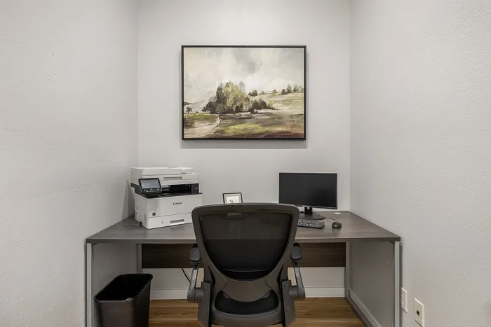 Cozy home office corner with desk, chair, and modern art on the wall, perfect for remote work.