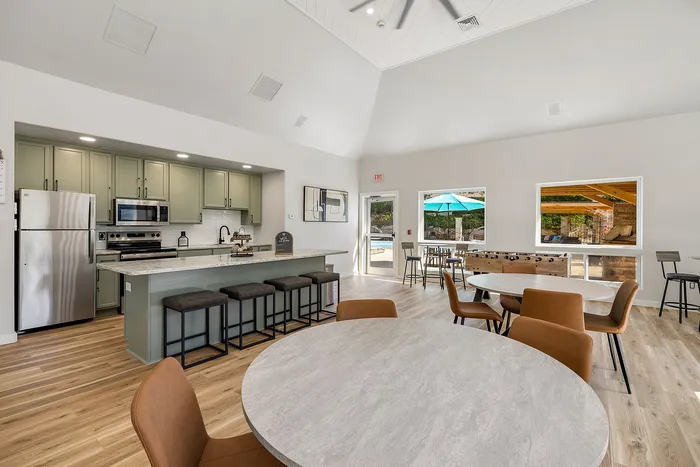 Elegant open-concept kitchen and seating area with modern appliances, stylish bar stools, and a view of the outdoor patio through large windows.