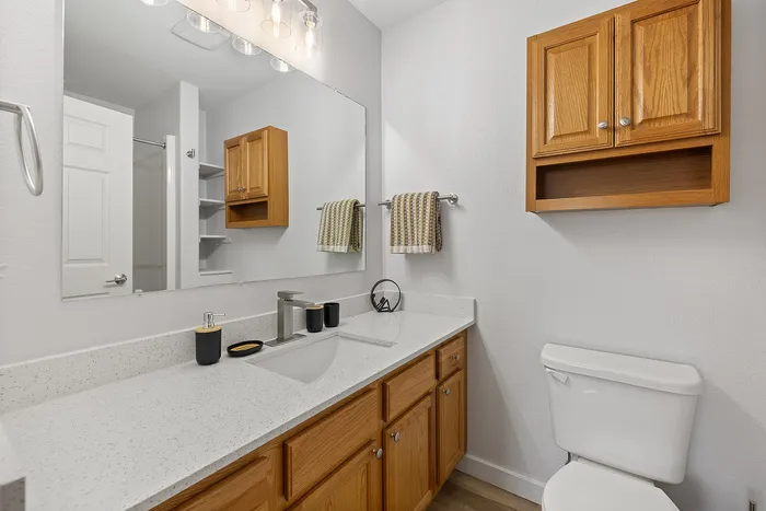 Bright and inviting bathroom with elegant quartz countertop, sleek fixtures, modern cabinetry, and ample storage space.
