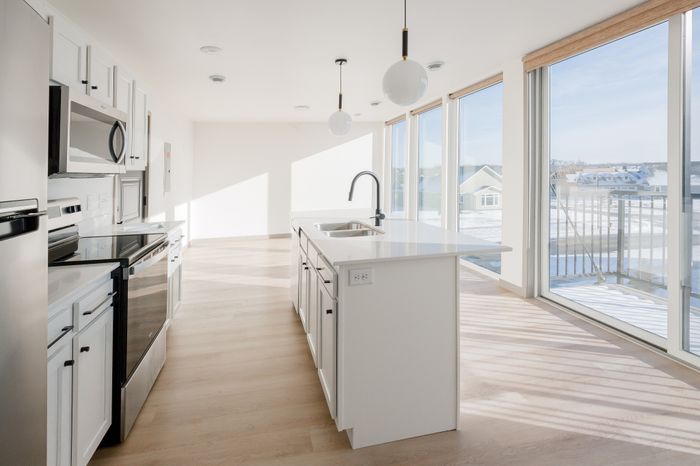 Bright and modern kitchen with sleek white cabinetry, stylish pendant lighting, and panoramic windows offering stunning outdoor views.