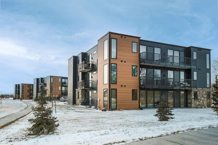Modern apartment complex with sleek architectural design, featuring spacious balconies and a winter landscape.