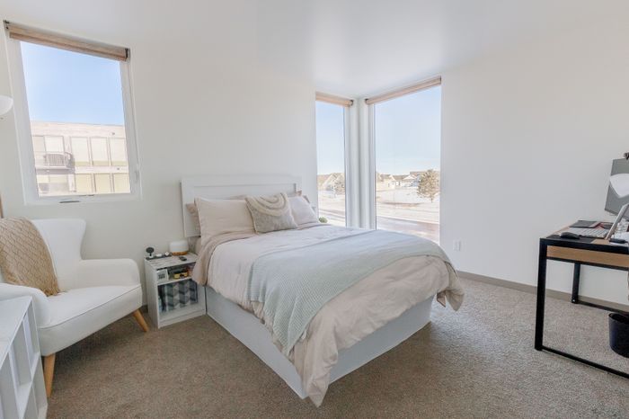 Bright and cozy bedroom featuring large windows, plush bedding, and modern decor with a serene view.