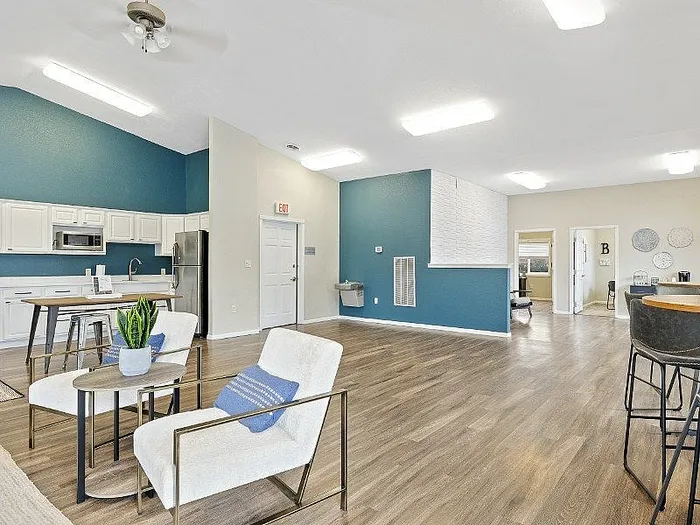 Modern open-concept living area with hardwood floors, stylish kitchen with a breakfast bar, and cozy lounge seating, enhanced by a vibrant accent wall.