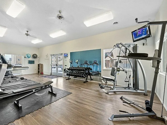 Modern fitness center featuring state-of-the-art treadmills, weight racks, and multi-exercise equipment on sleek hardwood floors.