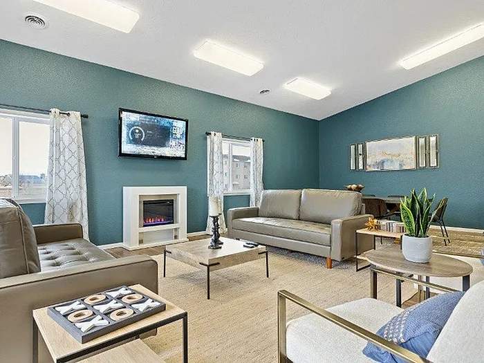 Inviting living room with modern sofas, elegant decor, wall-mounted TV, and a stylish fireplace set against a blue accent wall.