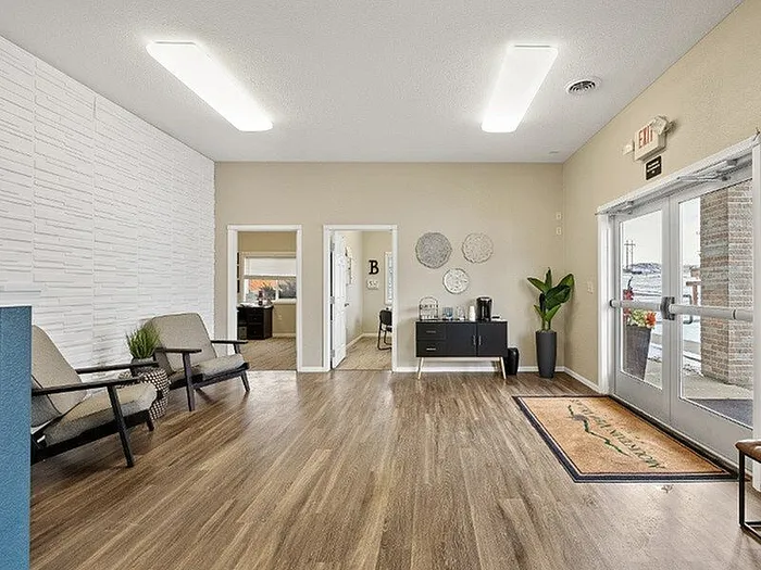 Inviting apartment lobby with elegant wood flooring, cozy seating area, and modern decor, offering a warm and welcoming atmosphere.