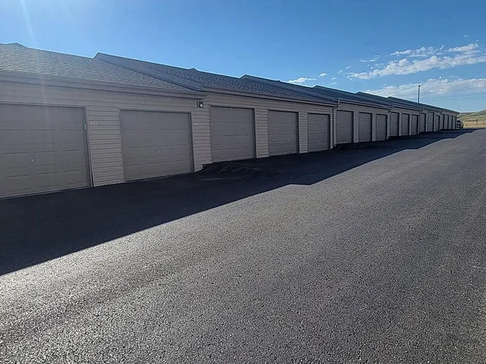 Modern and secure row of garages with pristine asphalt driveway under a clear blue sky, perfect for convenient parking and storage.