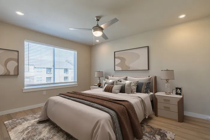Inviting modern bedroom with plush bedding, large window, and elegant decor in a stylish apartment setting.