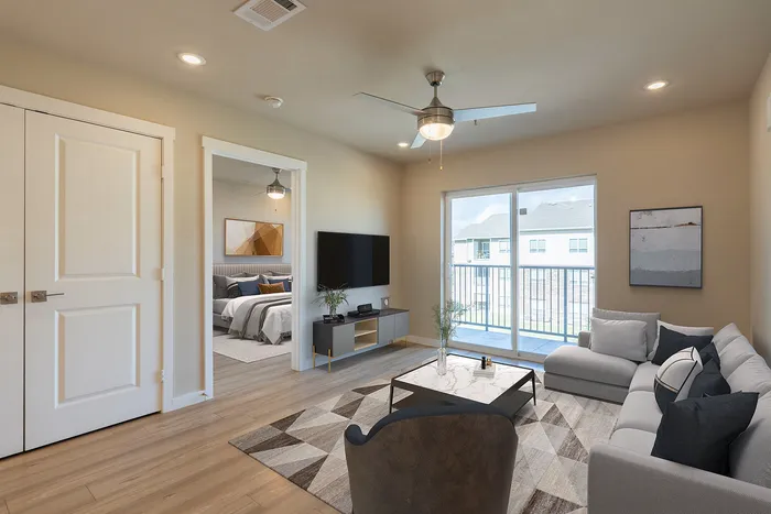 Modern living room with a cozy sectional sofa, elegant decor, and natural light from sliding glass doors opening to a balcony.