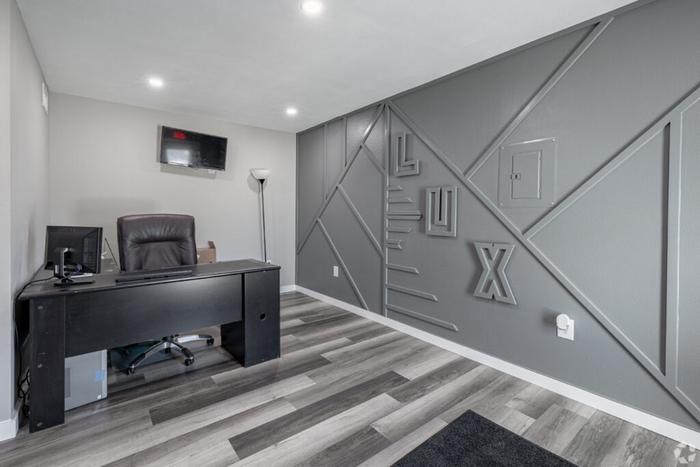 Modern office space with sleek gray accent wall, elegant desk, and flat-screen TV, ideal for productivity.