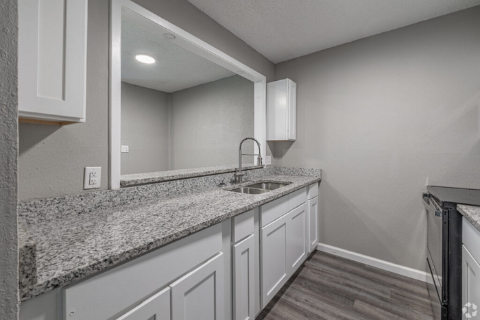 Modern kitchen with elegant granite countertops, sleek white cabinetry, and stainless steel fixtures, offering a stylish and functional space.