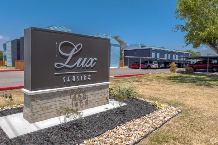 Inviting Lux Seaside property entrance with modern architecture, lush landscaping, and convenient parking.