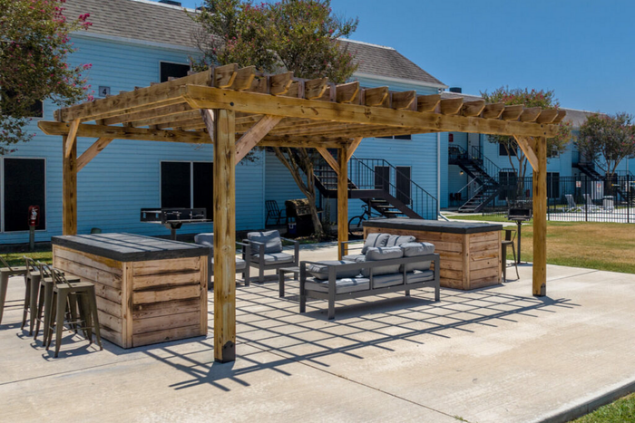 Charming outdoor area featuring a wooden pergola, comfortable seating, and stylish bar setup, perfect for relaxation and entertainment.