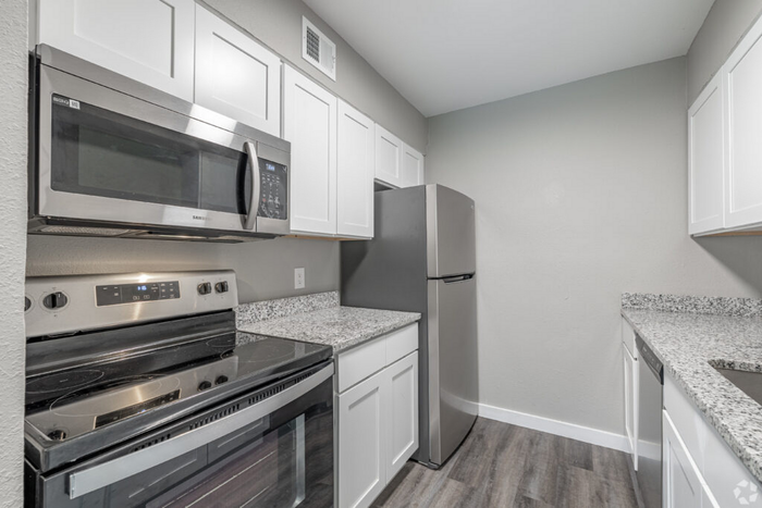 Modern kitchen with sleek stainless steel appliances, granite countertops, and stylish white cabinetry.
