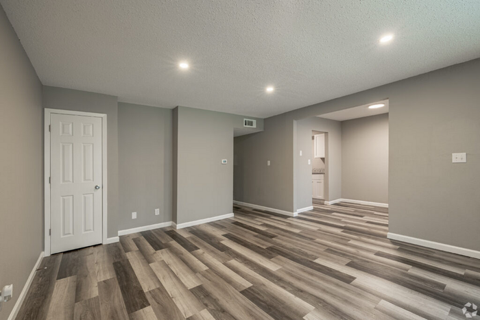 Modern open-concept living space with sleek wooden flooring, neutral walls, and abundant natural light.