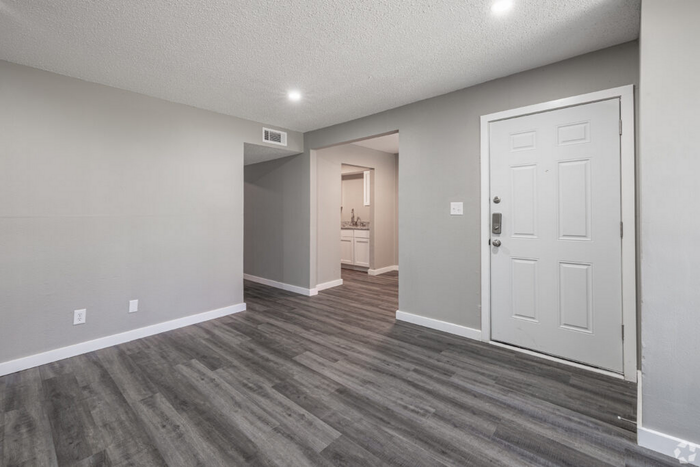 Modern apartment entryway with sleek laminate flooring, neutral gray walls, and bright overhead lighting leading to a spacious living area.