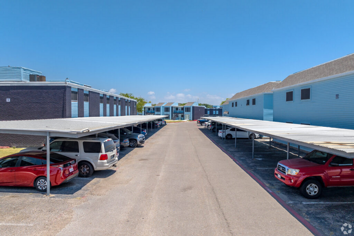 Spacious and well-organized apartment complex with convenient covered parking and modern architecture under a clear blue sky.