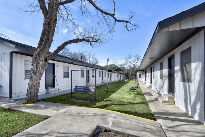 Charming apartment exterior with vibrant greenery and inviting pathways, creating a serene community atmosphere.