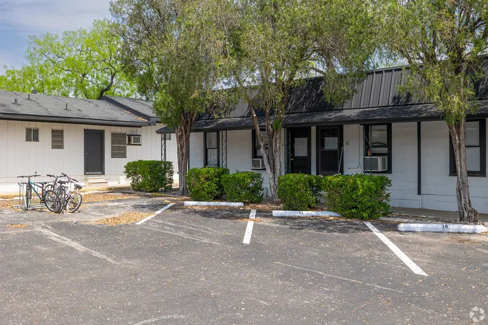 Charming apartment exterior with inviting porch, surrounded by lush greenery and convenient bike parking.
